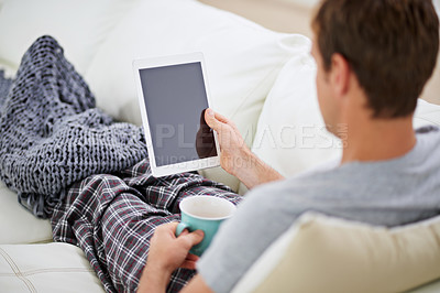 Buy stock photo Shot of a man in pajamas having coffee while using his digital tablet