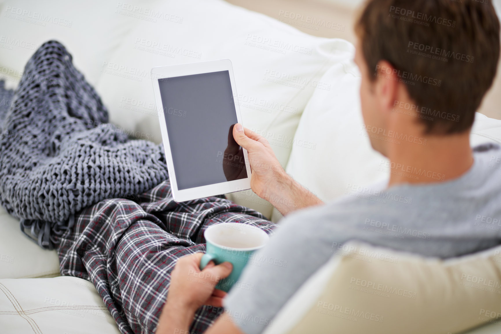 Buy stock photo Shot of a man in pajamas having coffee while using his digital tablet