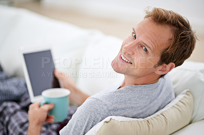 Buy stock photo Portrait of a man in pajamas having coffee while using his digital tablet