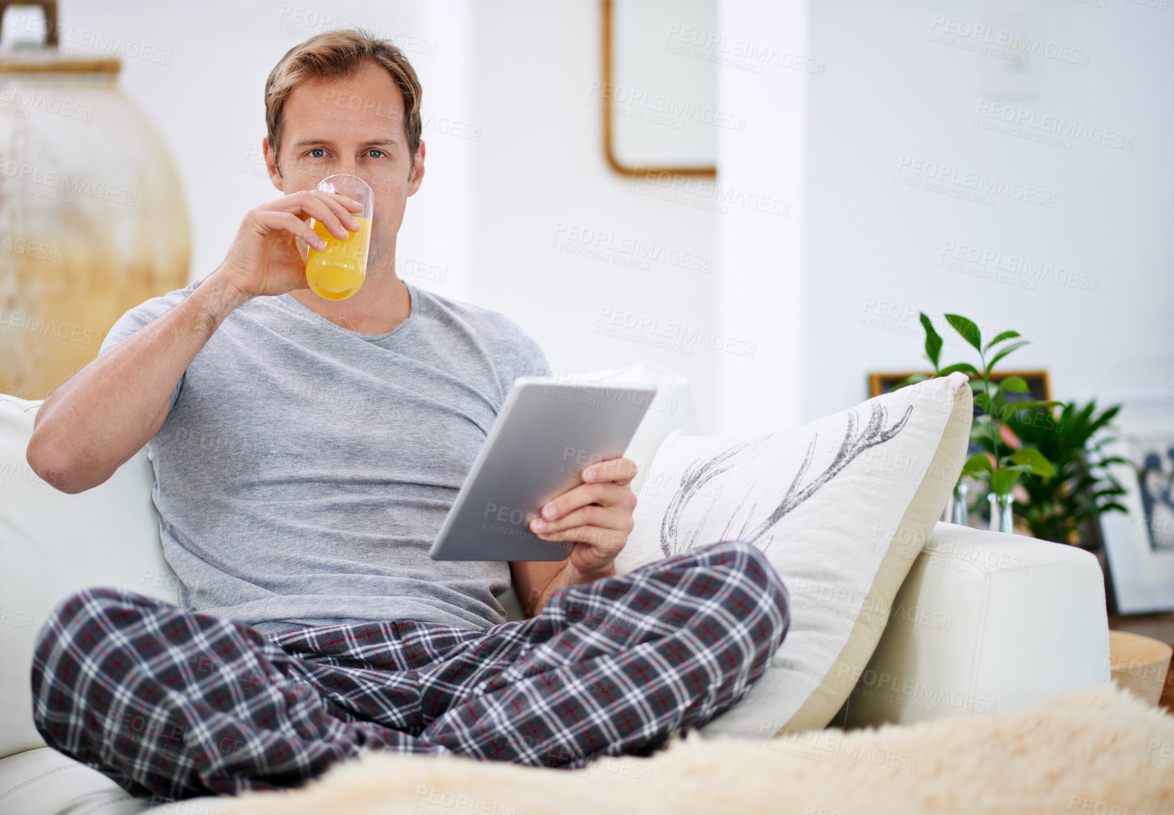 Buy stock photo Portrait, orange juice and man with tablet, pajamas and relax with morning news, digital app and connection. Person, home or guy on weekend break, nutrition and tech with health, wellness or internet