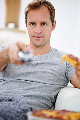 Buy stock photo Shot of a handsome man having pizza while watching tv