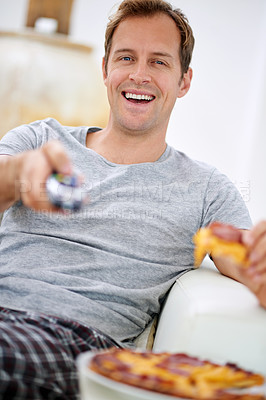 Buy stock photo Shot of a handsome man having pizza while watching tv