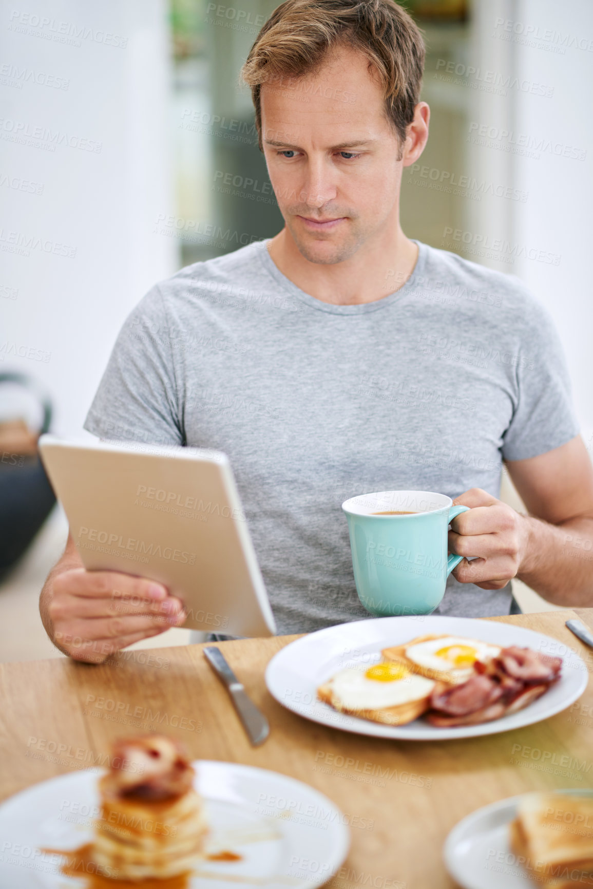Buy stock photo Man, tablet and morning breakfast or reading in home or nutrition meal with coffee, eggs or waffles. Male person, relax and online news in apartment kitchen for relax leisure, streaming or connection