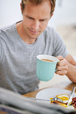 Buy stock photo Breakfast, man and newspaper in morning for news, articles and reports before work. Male person, coffee and tabloid at table for updates, current affairs and information at home while eating