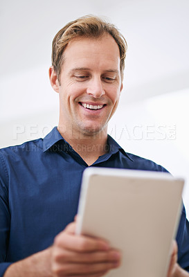 Buy stock photo Cropped shot of a handsome man using his tablet at home