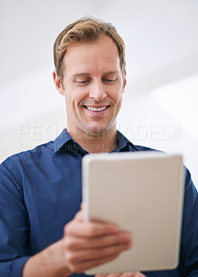 Buy stock photo Cropped shot of a handsome man using his tablet at home