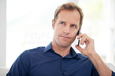 Buy stock photo Shot of a handsome man talking on his mobile phone at home