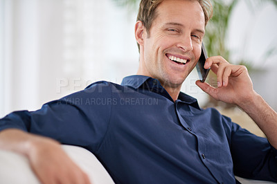 Buy stock photo Shot of a handsome man talking on his mobile phone at home