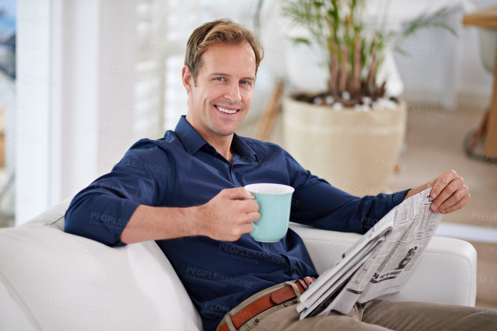 Buy stock photo Portrait of a handsome man having coffee while reading the paper at home
