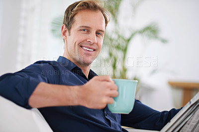 Buy stock photo Portrait of a handsome man having coffee while reading the paper at home