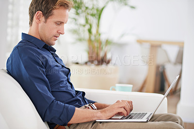 Buy stock photo Shot of a handsome man relaxing at home with his laptop