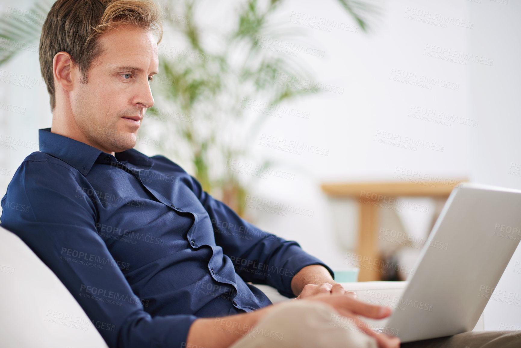 Buy stock photo Shot of a handsome man relaxing at home with his laptop