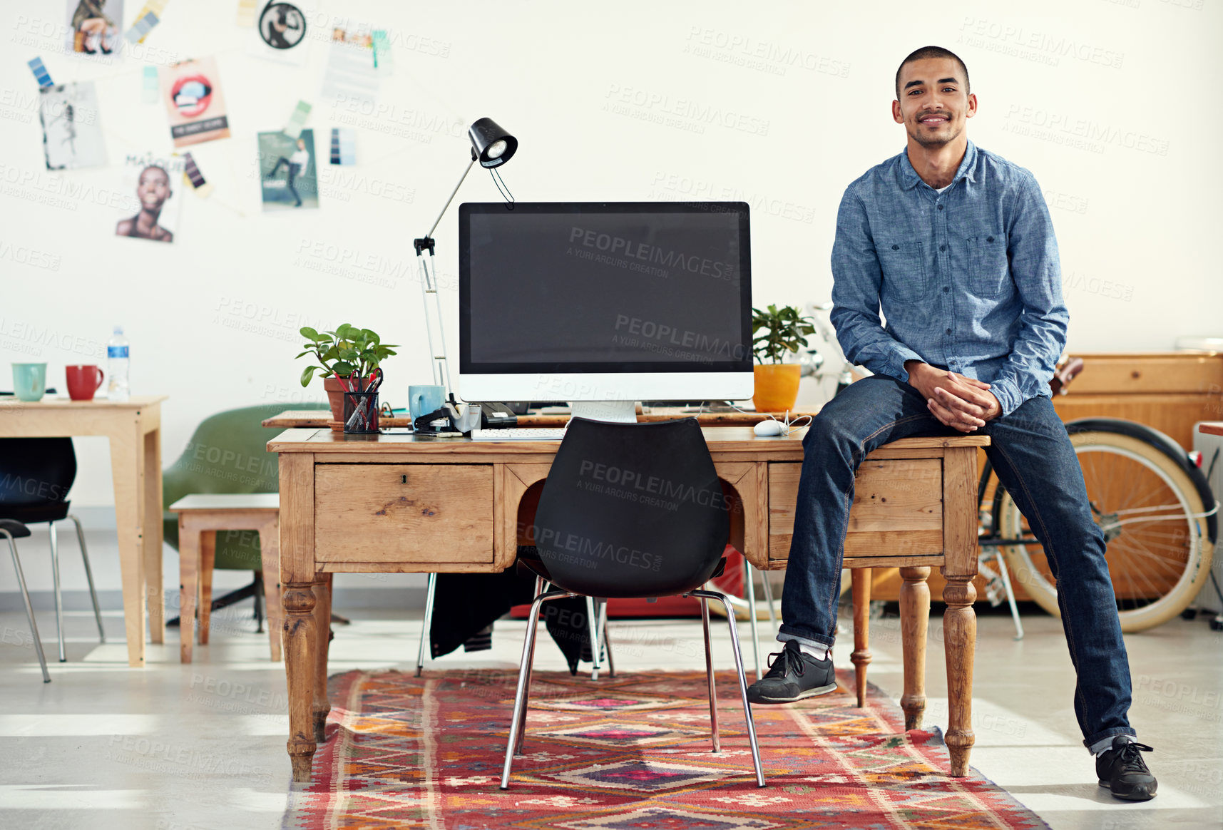 Buy stock photo Portrait of a casually-dressed young man sitting on his desk in an office