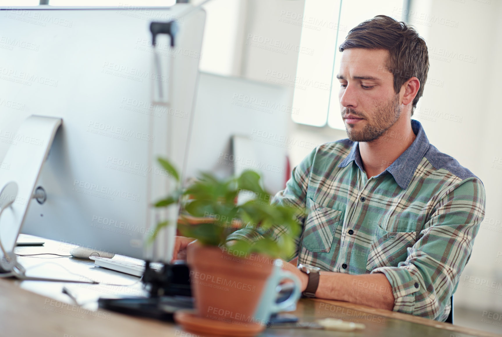 Buy stock photo Shot of a casually-dressed young man at work on a computer