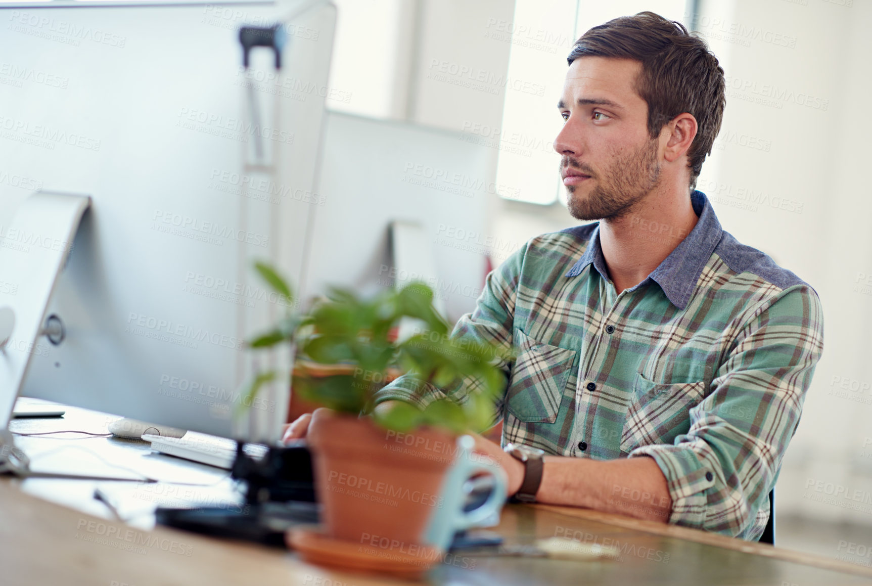 Buy stock photo Shot of a casually-dressed young man at work on a computer