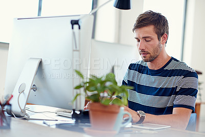 Buy stock photo Shot of a casually-dressed young man at work on a computer
