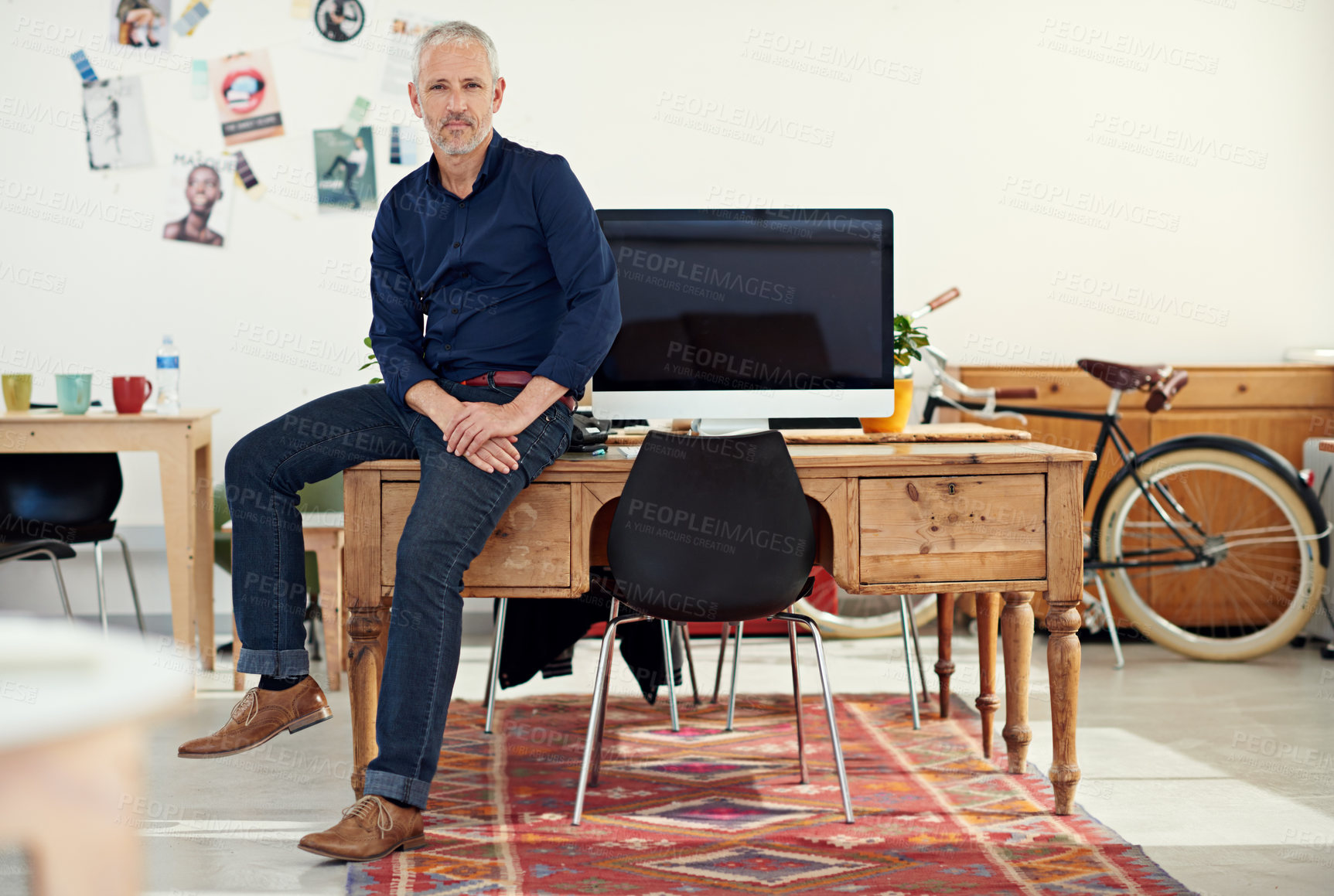 Buy stock photo Portrait of a casually-dressed mature man sitting on his desk in an office