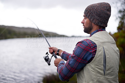 Buy stock photo Shot of a handsome man fishing at a natural lake