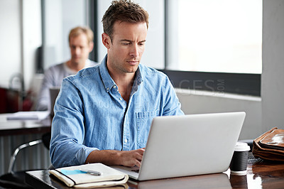 Buy stock photo Shot of a man working on a laptop in an office