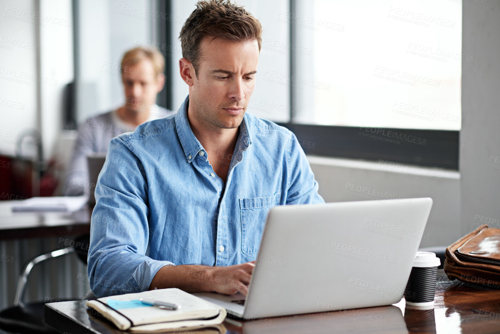 Buy stock photo Shot of a man working on a laptop in an office