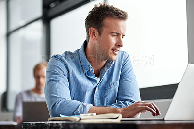 Buy stock photo Shot of a man working on a laptop in an office