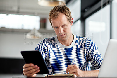 Buy stock photo Shot of a man working on a digital tablet and laptop in an office