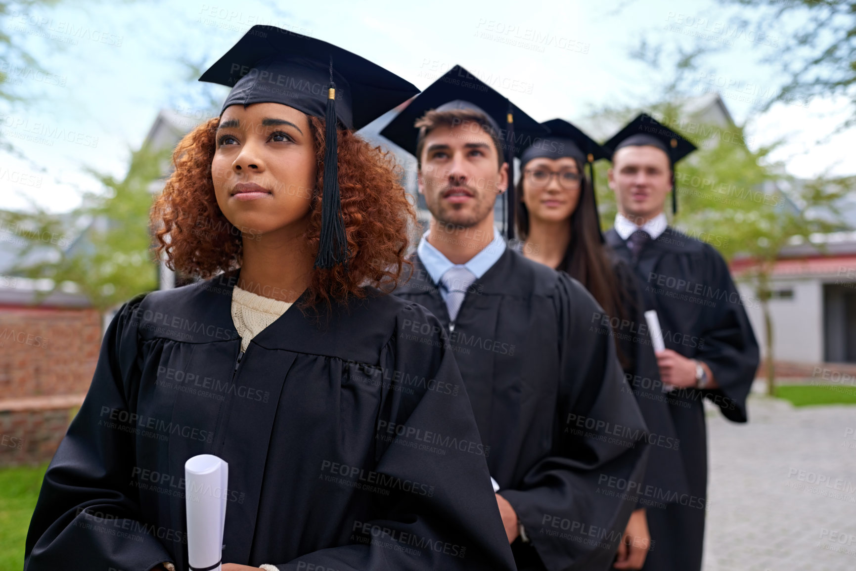 Buy stock photo Shot of graduating university students standing in a row looking up
