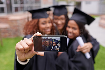 Buy stock photo Shot of three female graduates taking a picture of themselves on a phone