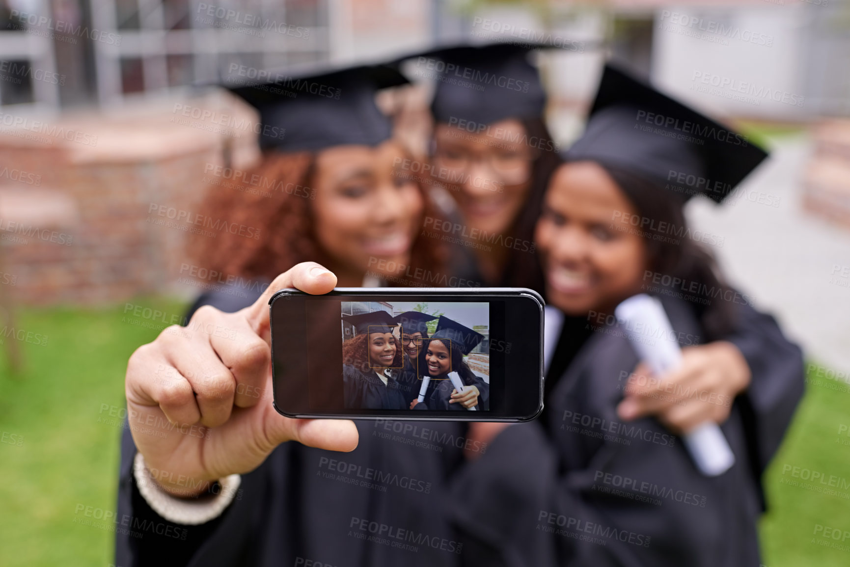 Buy stock photo Shot of three female graduates taking a picture of themselves on a phone