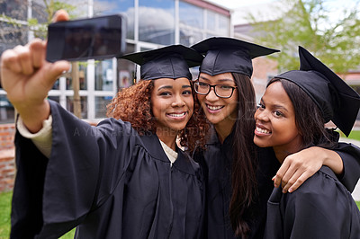 Buy stock photo Shot of three female graduates taking a selfie on a phone