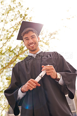 Buy stock photo Low angle portrait of young male graduate holding his degree