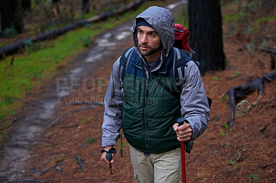 Buy stock photo Shot of a handsome man hiking in a pine forest using nordic walking poles
