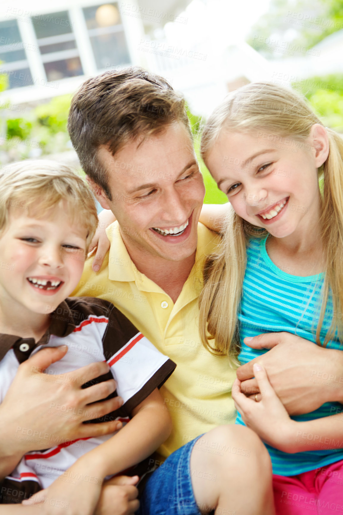 Buy stock photo Handsome young father holding his two children with a happy smile