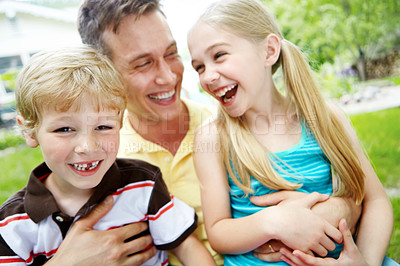 Buy stock photo Handsome young father holding his two children with a happy smile