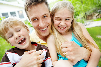 Buy stock photo Handsome young father holding his two children with a happy smile