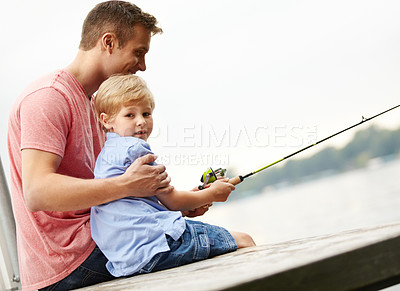 Buy stock photo A father teaching his son how to fish whilst sitting on a ledge over a river with copyspace