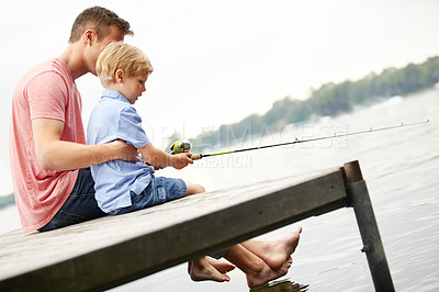 Buy stock photo A father teaching his son how to fish whilst sitting on a ledge over a river with copyspace