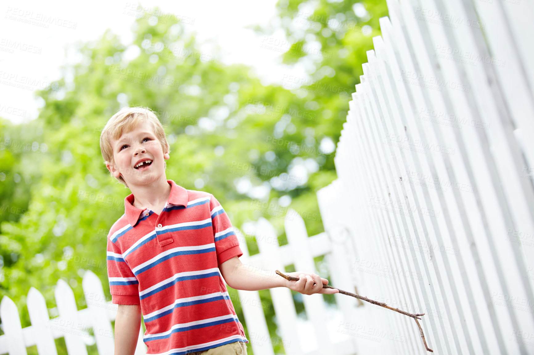 Buy stock photo Smile, stick and playful with kid and picket fence for fun, break and summer vacation. Happiness, explore and childhood development with young boy in backyard of home for holiday and outdoors