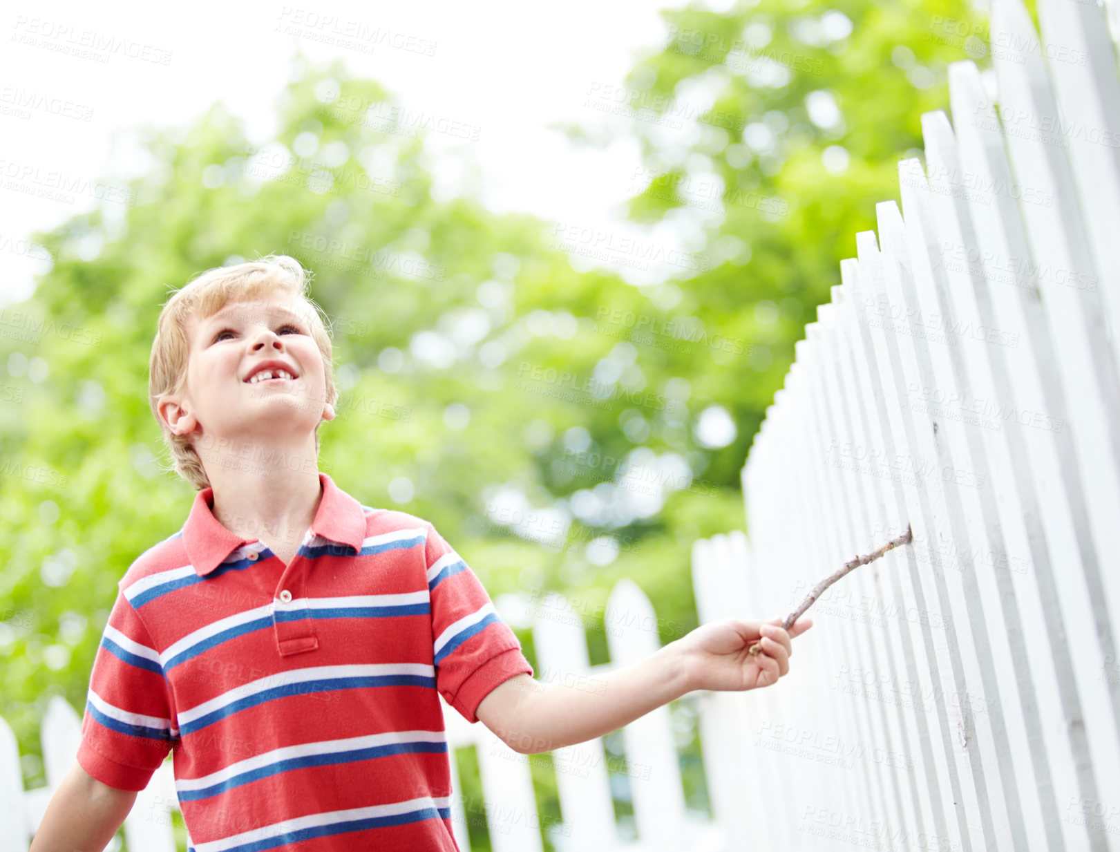 Buy stock photo Smile, freedom and playful with kid and picket fence for fun, break and summer vacation. Happiness, explore and childhood development with young boy in backyard of home for holiday and outdoors