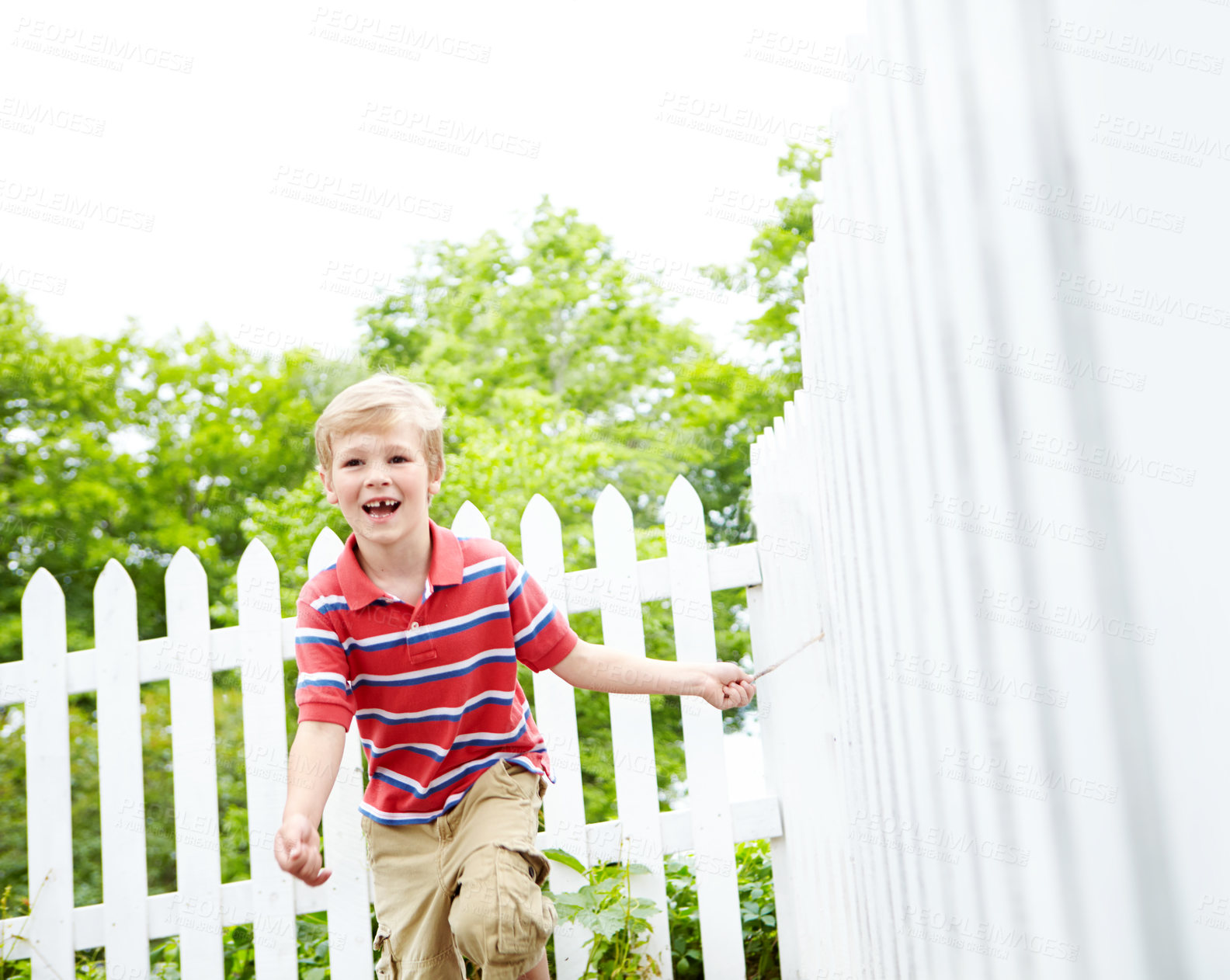 Buy stock photo Smile, running and playful with kid and picket fence for fun, break and summer vacation. Happiness, explore and childhood development with young boy in backyard of home for holiday and outdoors