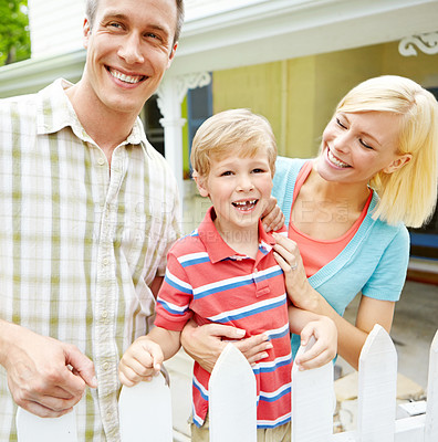 Buy stock photo Happy family, bonding and hug with child by fence for playful summer or weekend in backyard together. Mother, father and young kid with smile in joy for holiday or fun childhood in garden at home