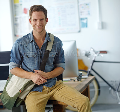 Buy stock photo A handsome young man with a satchel bag sitting on his desk