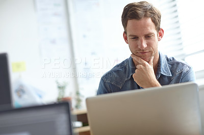 Buy stock photo A handsome young man working on his laptop in the office