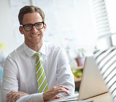 Buy stock photo A handsome young businessman working on his laptop