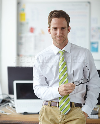 Buy stock photo A handsome young businessman holding his glasses while standing in the office