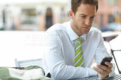 Buy stock photo A young businessman sitting outside while sending a text message