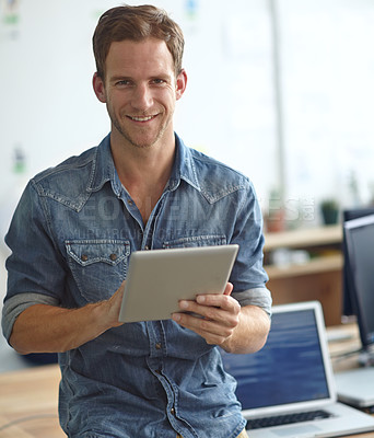 Buy stock photo A young man holdig a digital tablet while standing in his office