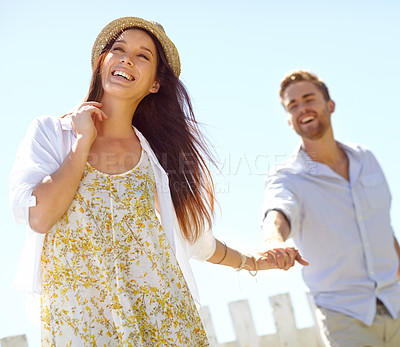 Buy stock photo Happy, young couple and holding hands with smile for summer vacation, travel or journey together in the outdoors. Beautiful woman leading her boyfriend by the hand on a sunny day for the holiday