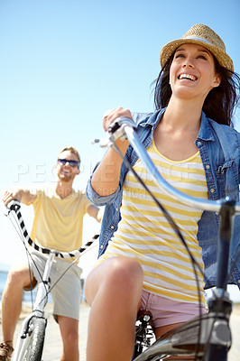 Buy stock photo Cycling, travel and couple with a woman on summer vacation or holiday riding on the promenade by the beach. Bike, freedom and date with a girlfriend outdoor for a ride on the coast during the day