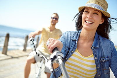 Buy stock photo Bike, cycling and couple with a travel woman on summer vacation or holiday riding on the promenade by the beach. Freedom, date and romance with a girlfriend outdoor for a ride on the coast